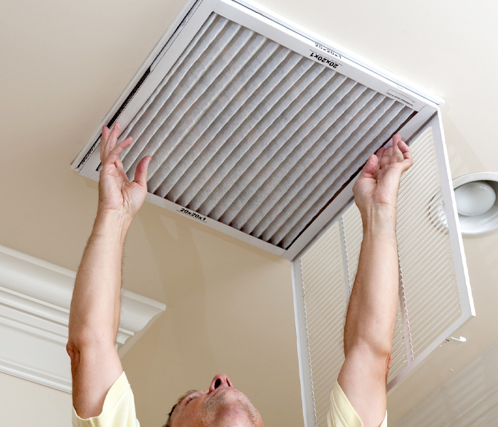 Changing out a ceiling vent filter.