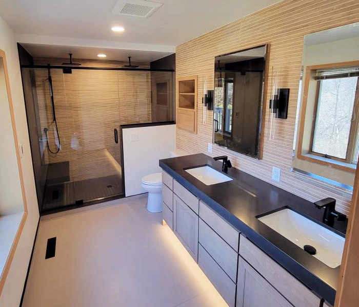 Remodeled bathroom with dual sinks, under-mount cabinet lights, large walk-in shower with glass door.