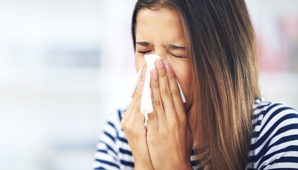 Woman blowing her nose due to summer allergies.