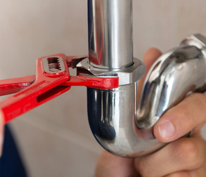 Plumbing pipe repair with a red wrench.