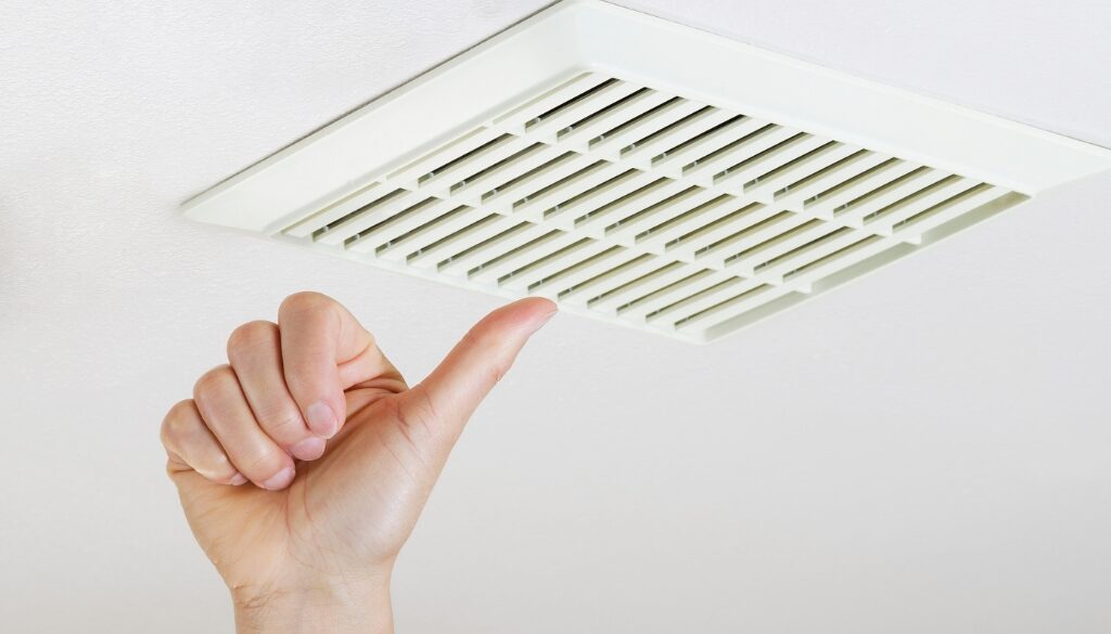 A hand giving a thumbs up next to a bathroom ventilation fan.