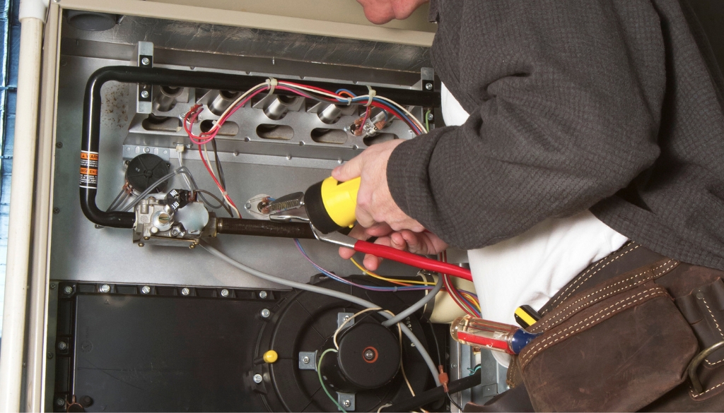 HVAC technician doing maintenance on a furnace.