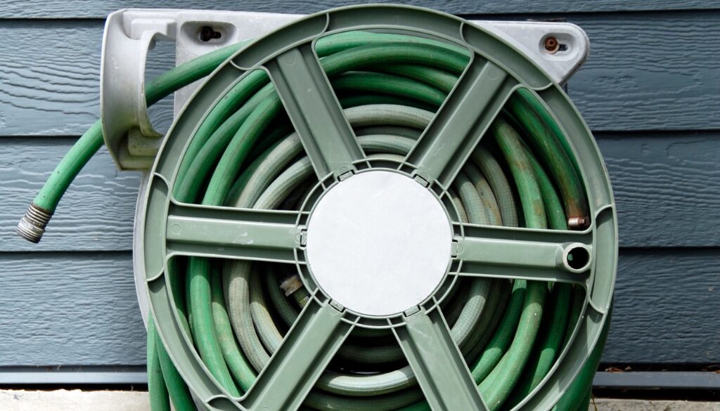 A close up of a green hose and holder on the side of a house.