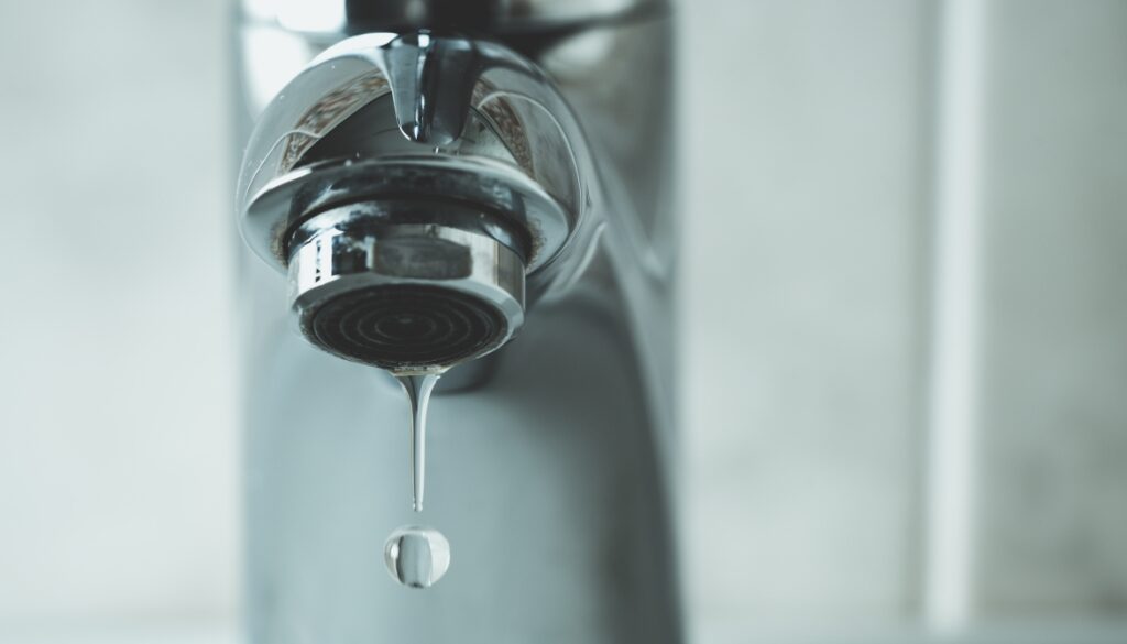 Close-up of a sink faucet dripping water to help prevent frozen pipes.