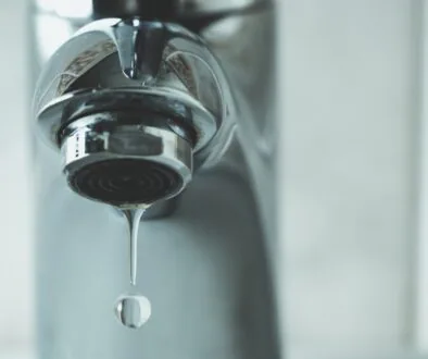 Close-up of a sink faucet dripping water to help prevent frozen pipes.