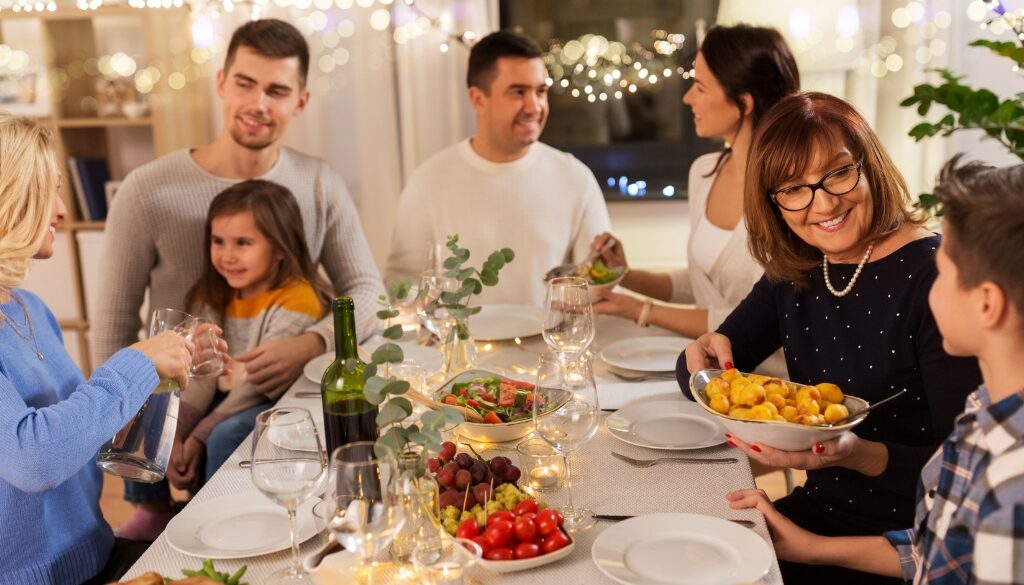 A family sitting around a dinner table, chatting and enjoying a holiday dinner together.