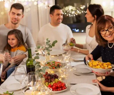 A family sitting around a dinner table, chatting and enjoying a holiday dinner together.