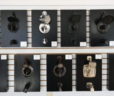 A display of various showerheads and faucet fixtures mounted on black panels in Niebuhr's showroom in La Crosse, Wisconsin, featuring brands like Kohler, Moen, and Pulse.