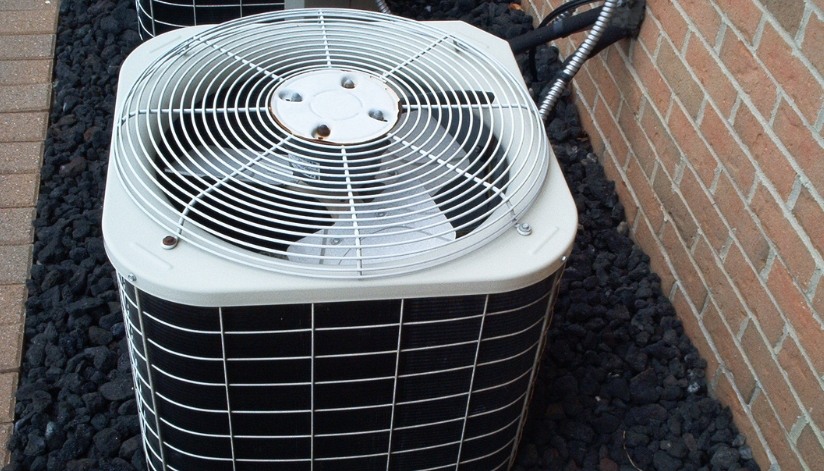 Should You Replace Or Repair Your Air Conditioner This Spring? Outdoor air conditioning unit next to a brick house.