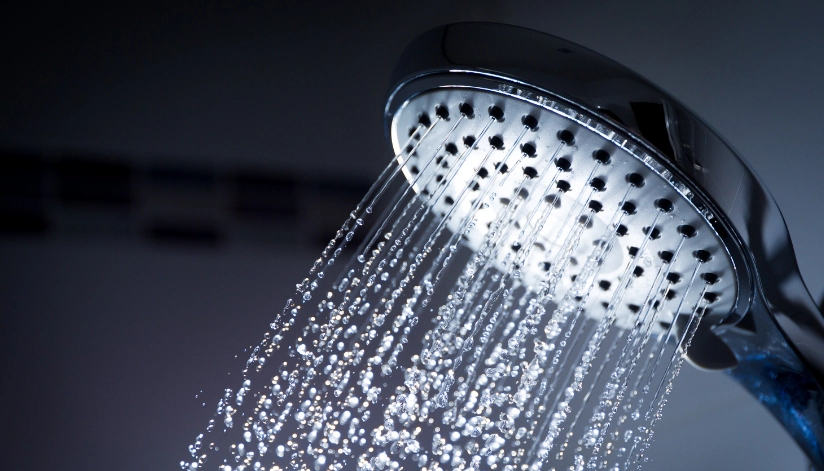 5 Ways To Conserve Water At Home Without Sacrificing Comfort A modern showerhead spraying water, representing water conservation and efficient plumbing solutions for the home.