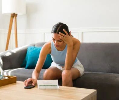 A concerned woman reviews a high energy bill while adjusting her air conditioner.