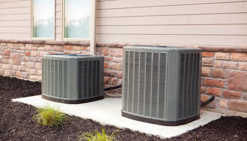 How To Choose The Right Air Conditioner For Your Home Two central air conditioning units installed outside a residential home.