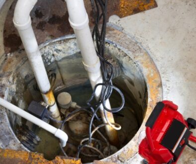 A basement sump pit showing multiple pipes and wiring.