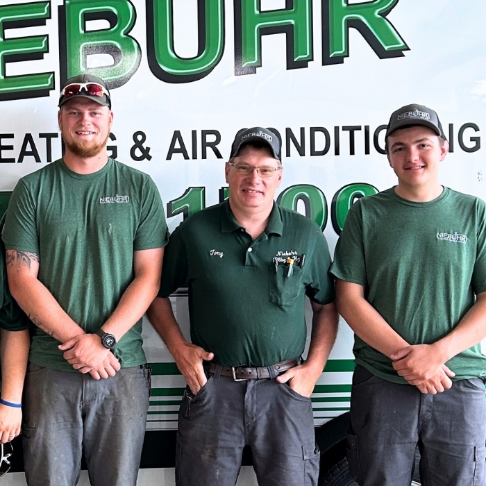 Wes, Tony, and Logan of Niebuhr Plumbing, Heating, and Air Conditioning standing in front of a Niebuhr truck.