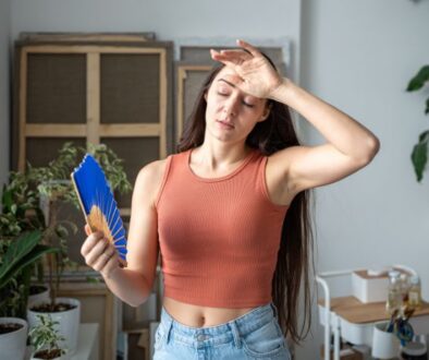 Woman fans herself as her house feels humid even when AC is running.