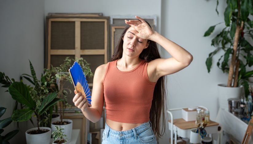 Woman fans herself as her house feels humid even when AC is running.