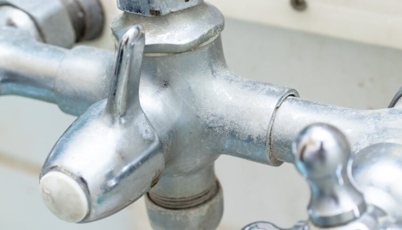 Silver faucet with hard water stains.